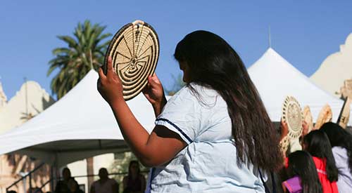 Indigenous person holding up woven art piece