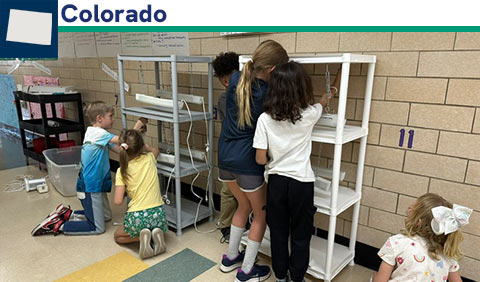 Students working together at carts with grow lights; small map of Colorado