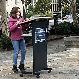 Child holding microphone and standing at lectern