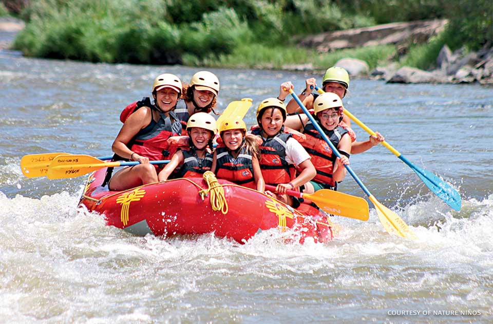 An image of children smiling while rafting.