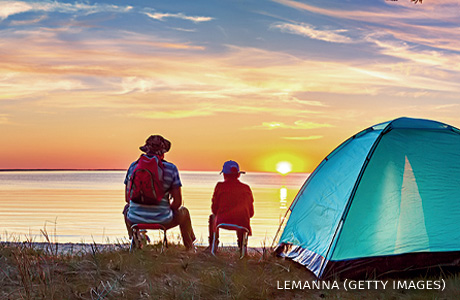 An image of a family resting with a tent in nature at sunset.