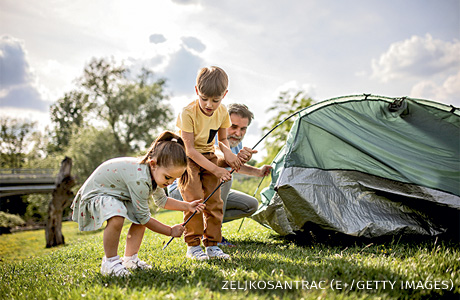 An image of a multigenerational family camping and setting up a tent.