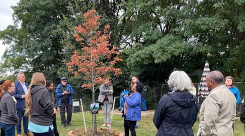 Group of people gathered around tree with Certified Wildlife Habitat sign